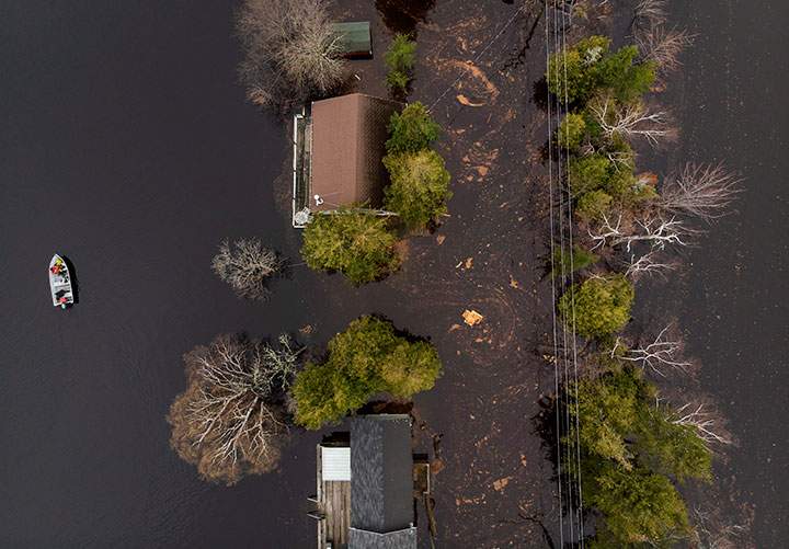 A boat drives next to cottages and homes along a flooded roadway on Grand Lake, N.B. as floodwaters continue to rise from the Saint John River on Tuesday, May 1, 2018.