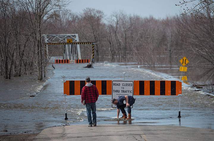 Residents move the barricade out of the rising floodwater from the Saint John River in Lakeville Corner, N.B. on Wednesday, May 2, 2018.