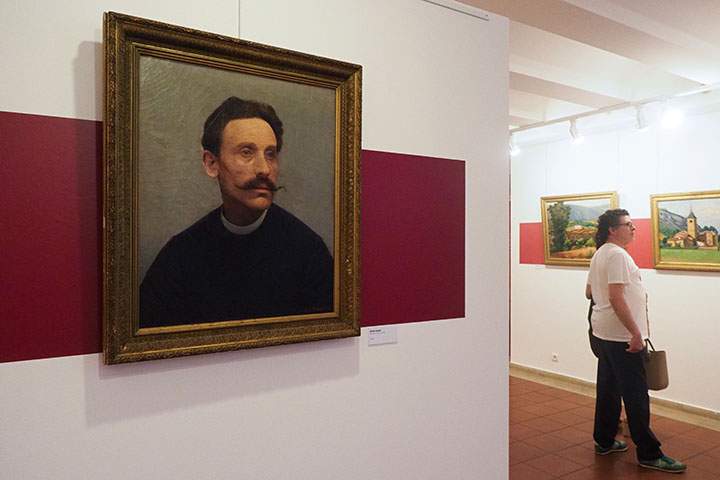 Visitors look at the painting "Le clocher de Ria" next to "Portrait d'un inconnu" at the museum dedicated to French painter Etienne Terrus, in Elne on April 28, 2018. 