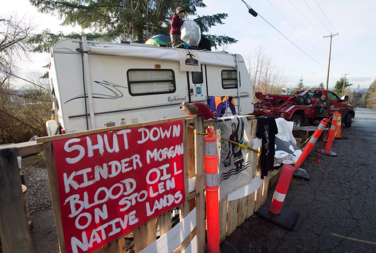 A protester who goes by the name Uni stands on top of a trailer outside the main gates of Kinder Morgan in Burnaby, B.C., Wednesday, Jan. 10, 2018.