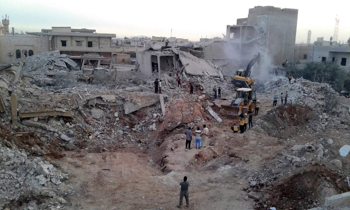This photo provided by the Syrian Civil Defense White Helmets, which has been authenticated based on its contents and other AP reporting, shows civil defense workers and civilians inspecting damaged buildings after airstrikes hit in the village of Zardana, in Idlib province, Syria, Friday, June 8, 2018.