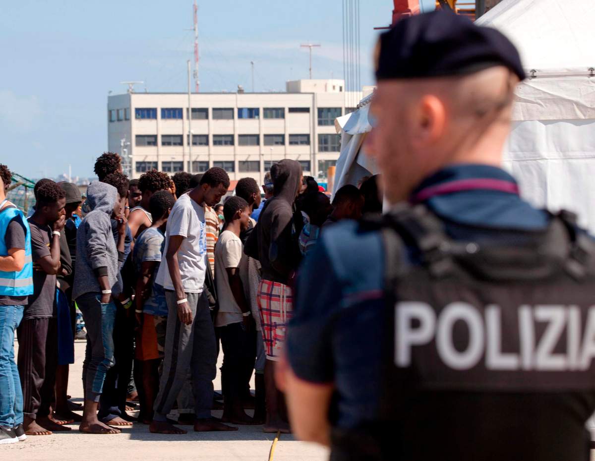 FILE – In this Saturday, June 9, 2018 filer, migrants line-up after disembarking at the Reggio Calabria harbor, Southern Italy.