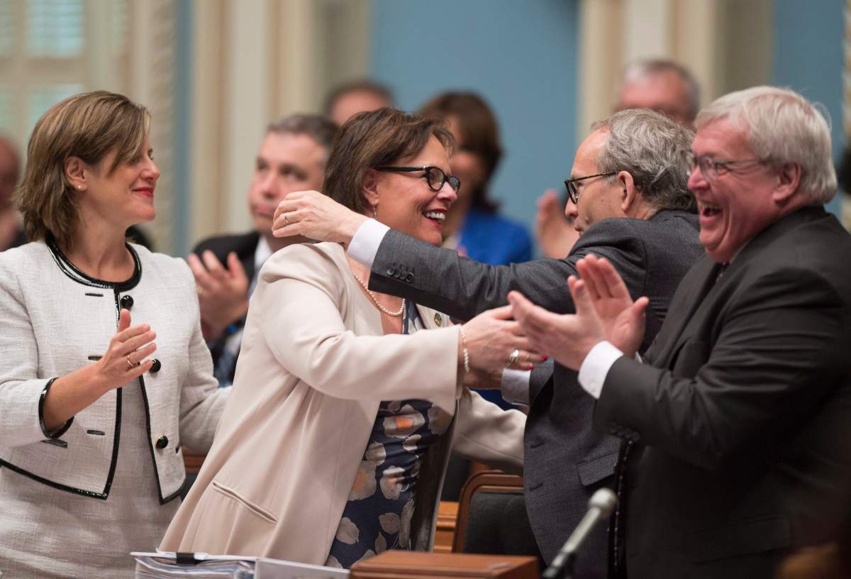 Quebec Minister for Rehabilitation, Youth Protection and Public Health Lucie Charlebois, centre, is congratulated by Quebec Public Security Minister and Municipal Affairs Minister Martin Coiteux, right.