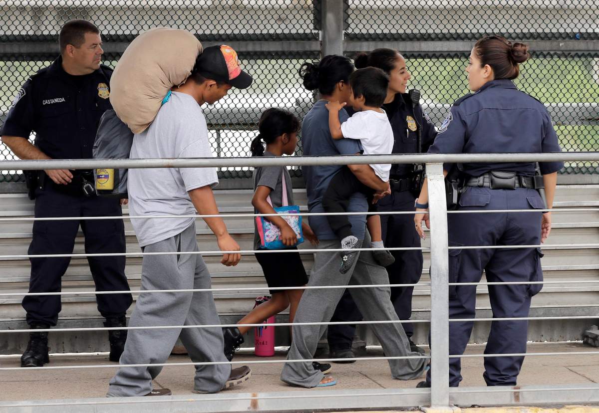 Ever Castillo, left, and his family, immigrants from Honduras, are escorted back across the border by U.S. Customs and Border Patrol agents Thursday, June 21, 2018, in Hildalgo, Texas. The parents were told they would be separated from their children and voluntarily crossed back to Mexico after trying to seek asylum in the United States. (AP Photo/David J. Phillip).