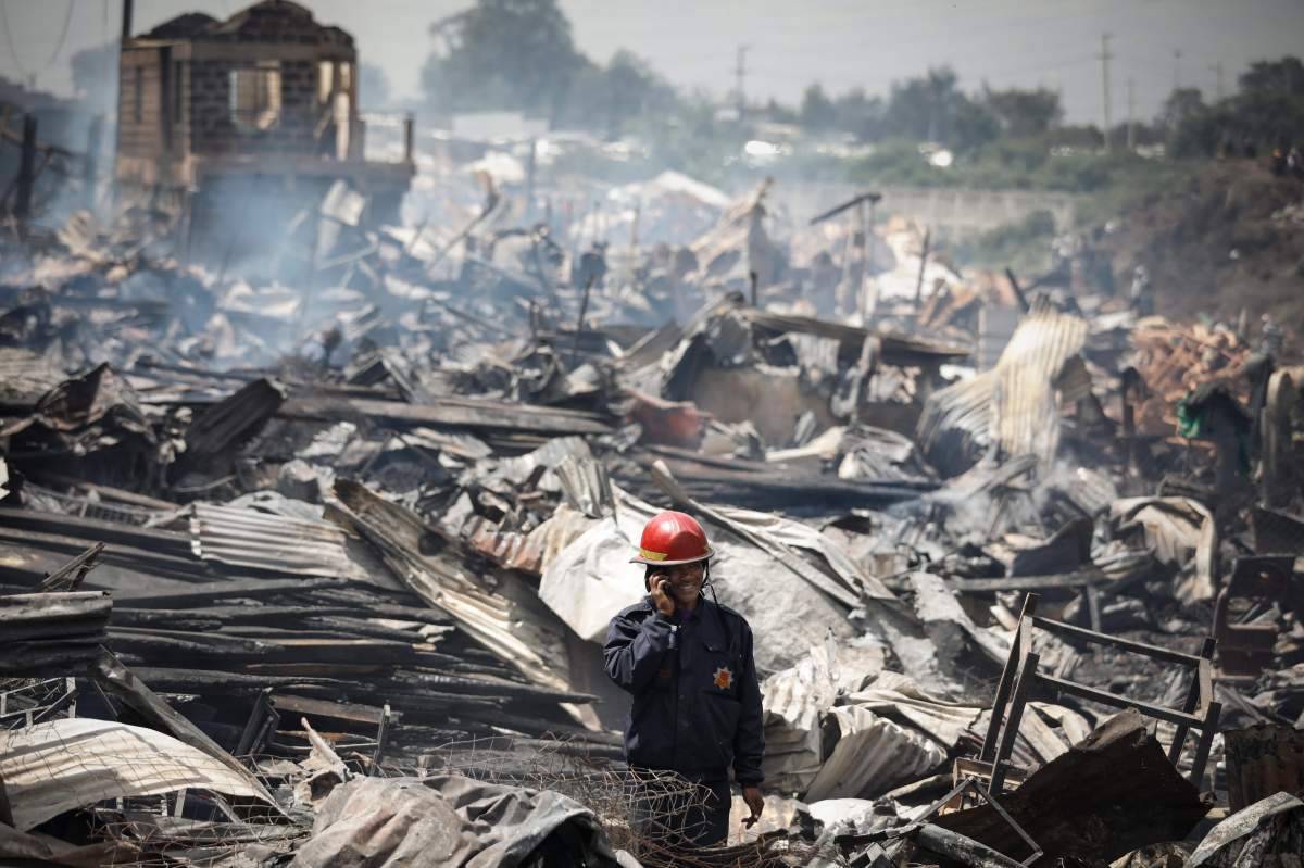 A rescue worker stands in midst of the rubble after a huge fire burned down timber shops in Gikomba market in Nairobi, Kenya, 28 June 2018.