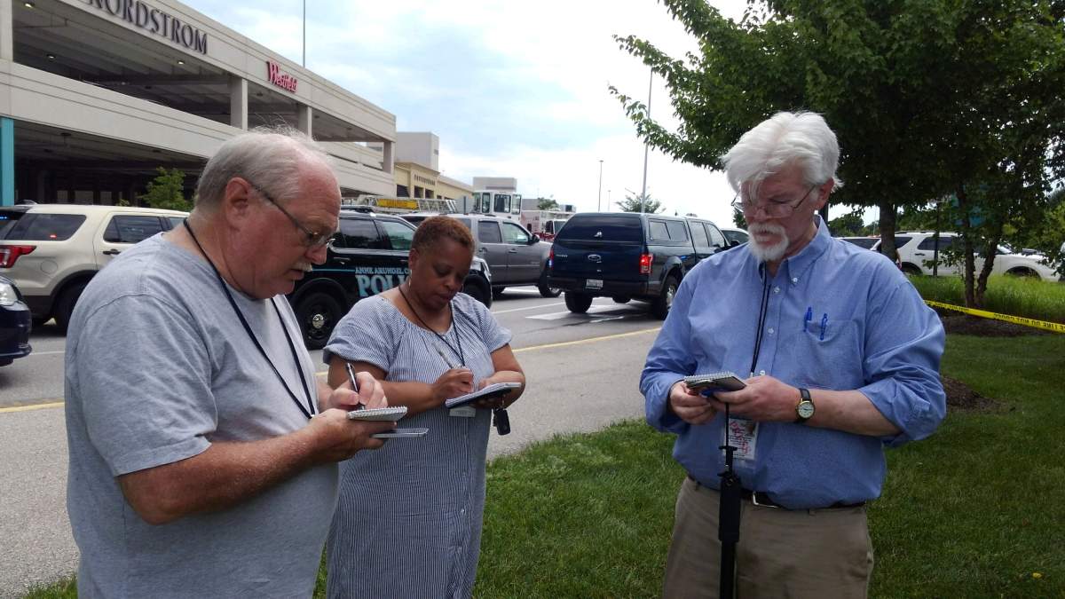 Captial Gazette Journalist E.B Furgurson (R) takes notes with two other people as police officers respond to an active shooter inside a city building at the Capital Gazette newspaper office in Annapolis, Maryland, U.S., June 28, 2018.