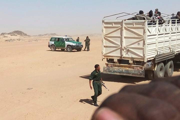In this Tuesday, May 8, 2018 photo provided by Liberian migrant Ju Dennis, Algerian gendarmes carrying AK-47 assault rifles load migrants onto trucks to drop them off near the Niger border. Dennis filmed his deportation with a cell phone he kept hidden.