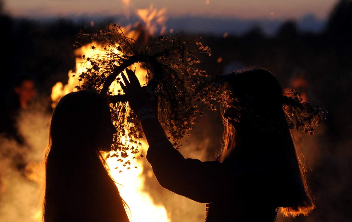 TOPSHOT – Two girls put traditional wreaths near a bonfire as they take part in the Ivan Kupala Night celebration, a traditional Slavic holiday, outside the small town of Turov, some 270 km south of Minsk, on July 6, 2016.