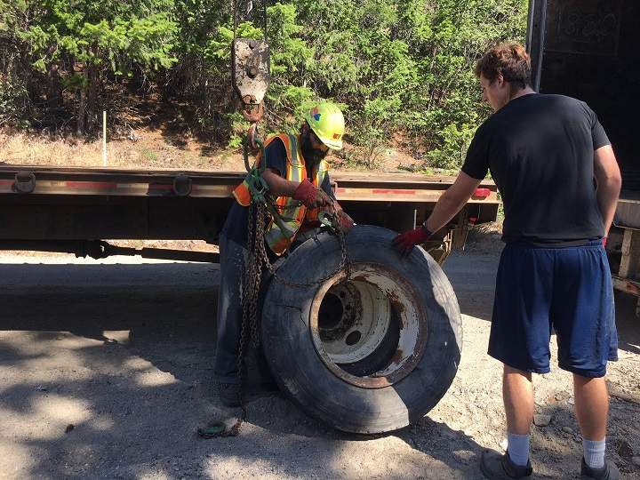 A worker loads a tire onto a flat deck truck during Tuesday’s clean-up session.
