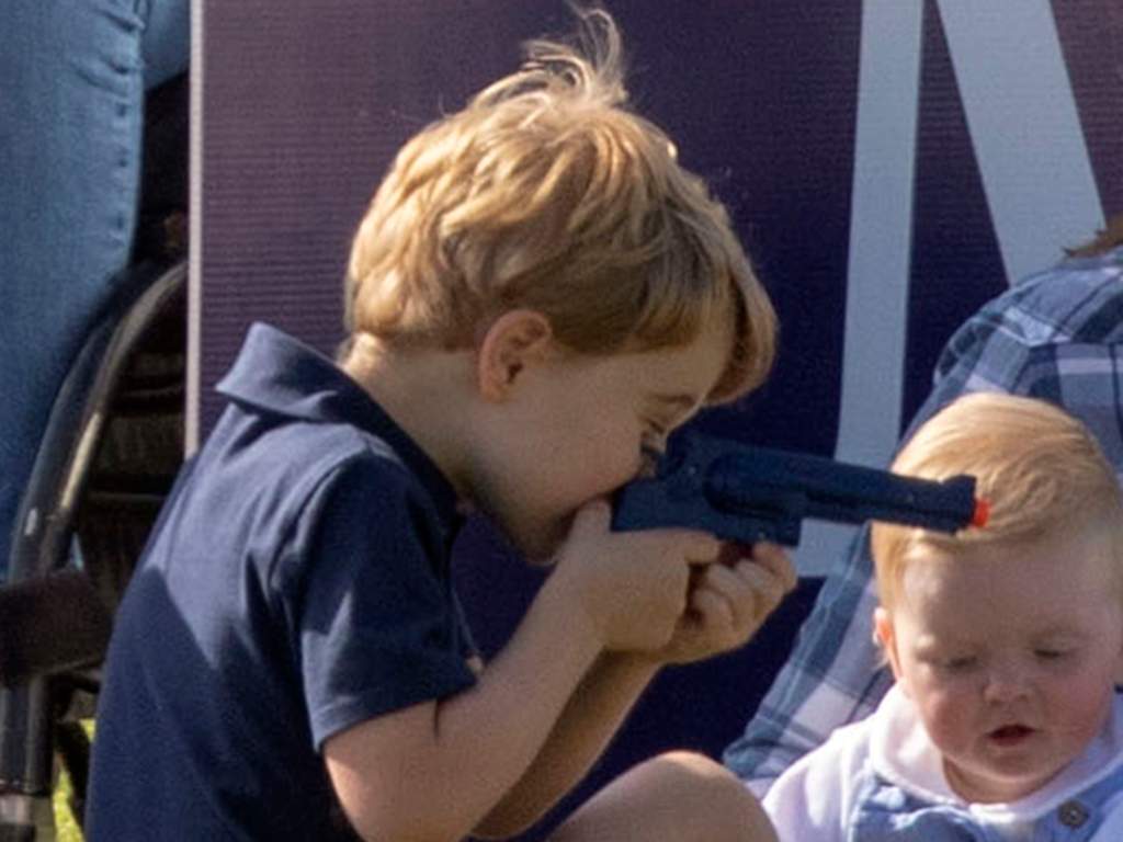 Prince George plays with a toy gun at the Maserati Royal Charity Polo Trophy.