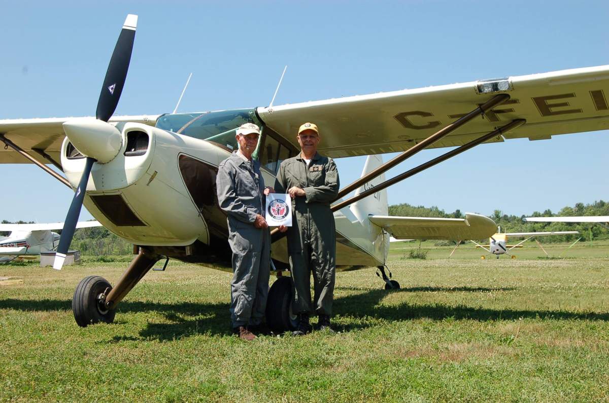 Terry Peters and Oliver Javanpour pose in front of the vintage Stinson 108 aircraft they flew from coast to coast. 