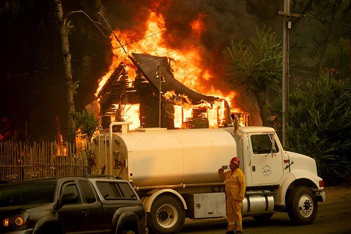 A water tender operator drinks a beverage after trying to save a home burning in Shasta, Calif., on Thursday, July 26, 2018.