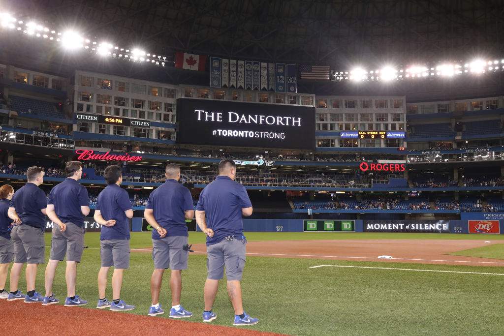 Members of the grounds crew stand in tribute to the victims of the Danforth shooting Sunday night before the start of the Toronto Blue Jays MLB game against the Minnesota Twins at Rogers Centre on July 23 in Toronto. (Photo by Tom Szczerbowski/Getty Images)