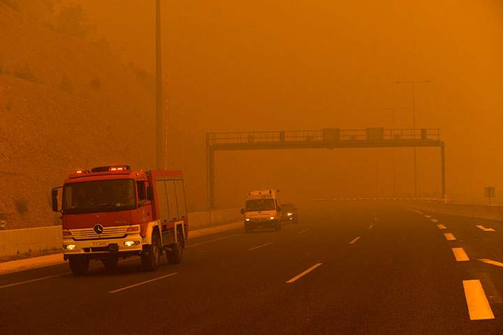 A firetruck are seen amid smoke as a wildfire burns in Kineta, near Athens, on July 23, 2018.