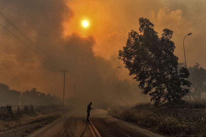 A firefighter tries to extinguish hotspots during a wildfire in Kineta, near Athens, on July 23, 2018.
