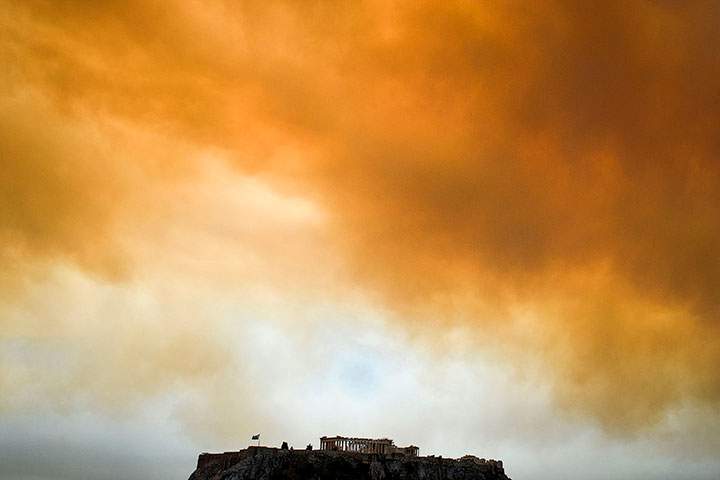 A picture taken on July 23, 2018 shows the Parthenon temple on the Acropolis hill in Athens as smoke billows in background during a wildfire in Kineta, near Athens.