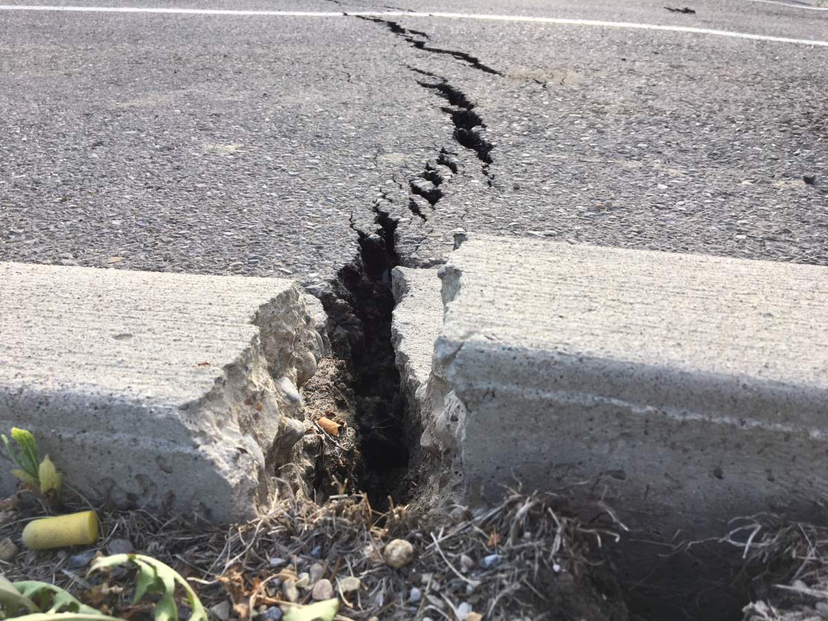 Cracked ground is seen at the site of a sinkhole that appeared in the Crowfoot LRT parking lot on Tuesday.