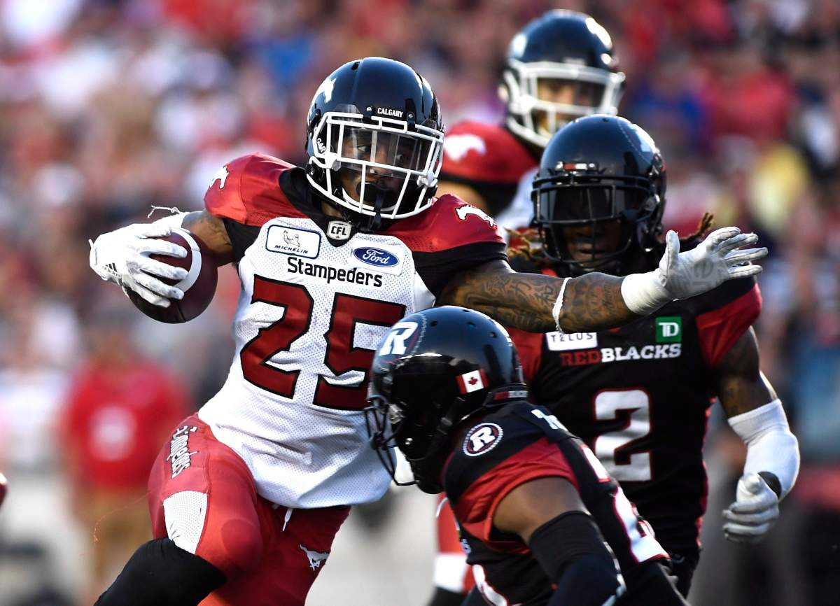 Calgary Stampeders Don Jackson (25) tries to make his way past Ottawa Redblacks Josh Johnson (2) during first half CFL action in Ottawa on Thursday, July 12, 2018. THE CANADIAN PRESS/Justin Tang.
