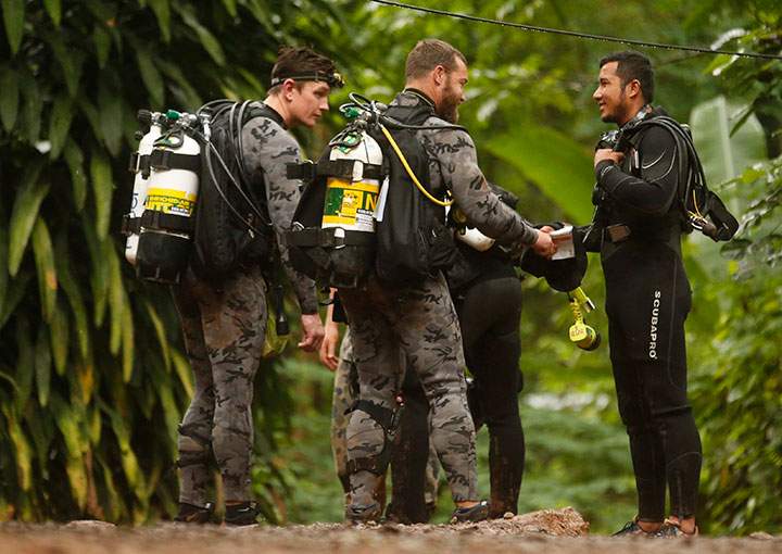 Australian Federal Police and Defense Force personnel talk to a Thai rescuer, right, before diving for the 12 boys and their soccer coach were found alive, in Mae Sai, in northern Thailand, July 3, 2018.