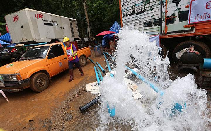 A Thai rescuer walks near where water is pumped from a flooded cave after all 12 boys and their soccer coach were found alive, in Mae Sai, in northern Thailand on July 3, 2018.