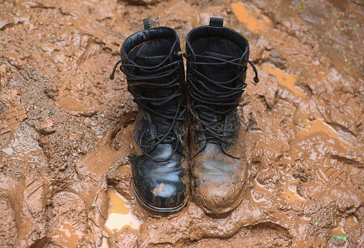 In this Thursday, June 28, 2018,photo, a pair of boots sit in thick mud at the staging area for search and rescue efforts for a missing soccer team and their coach in a large cave in Mae Sai, Chiang Rai province, in northern Thailand.