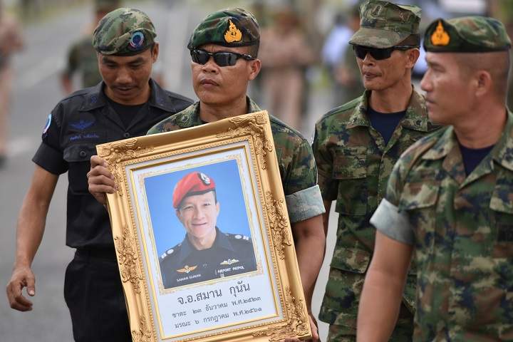 An honour guard holds up a picture of Samarn Kunan, 38, a former member of Thailand’s elite navy SEAL unit who died working to save 12 boys and their soccer coach trapped inside a flooded cave in Rayong province, Thailand, July 6, 2018.