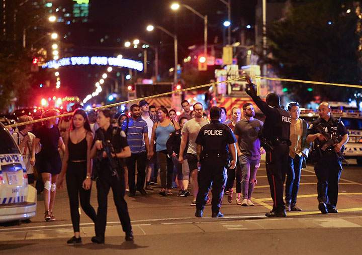People leave an area taped off by the police near the scene of a mass shooting in Toronto, Canada, July 22, 2018.