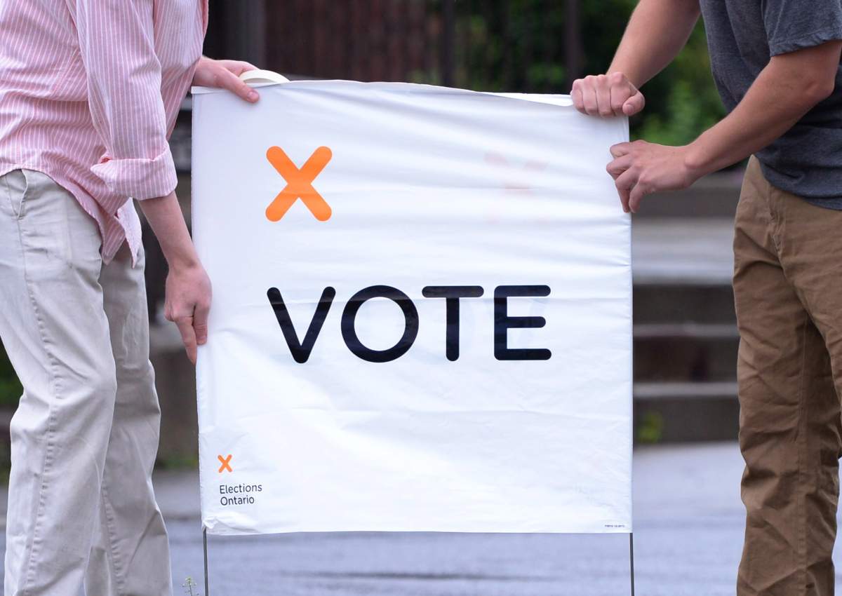 Poll station workers place a vote sign in preparation for voters on election day in 2014. 