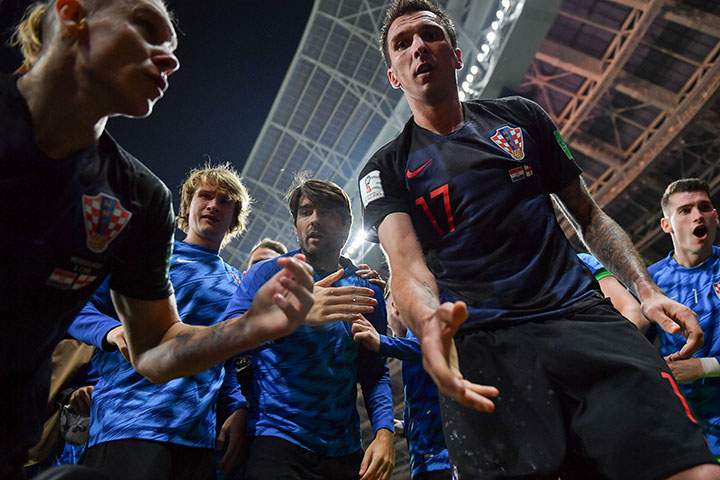 Croatia’s forward Mario Mandzukic offers to help AFP photographer Yuri Cortez after he fell on him with teammates while celebrating their second goal during the Russia 2018 World Cup semi-final between Croatia and England at the Luzhniki Stadium in Moscow on July 11, 2018.