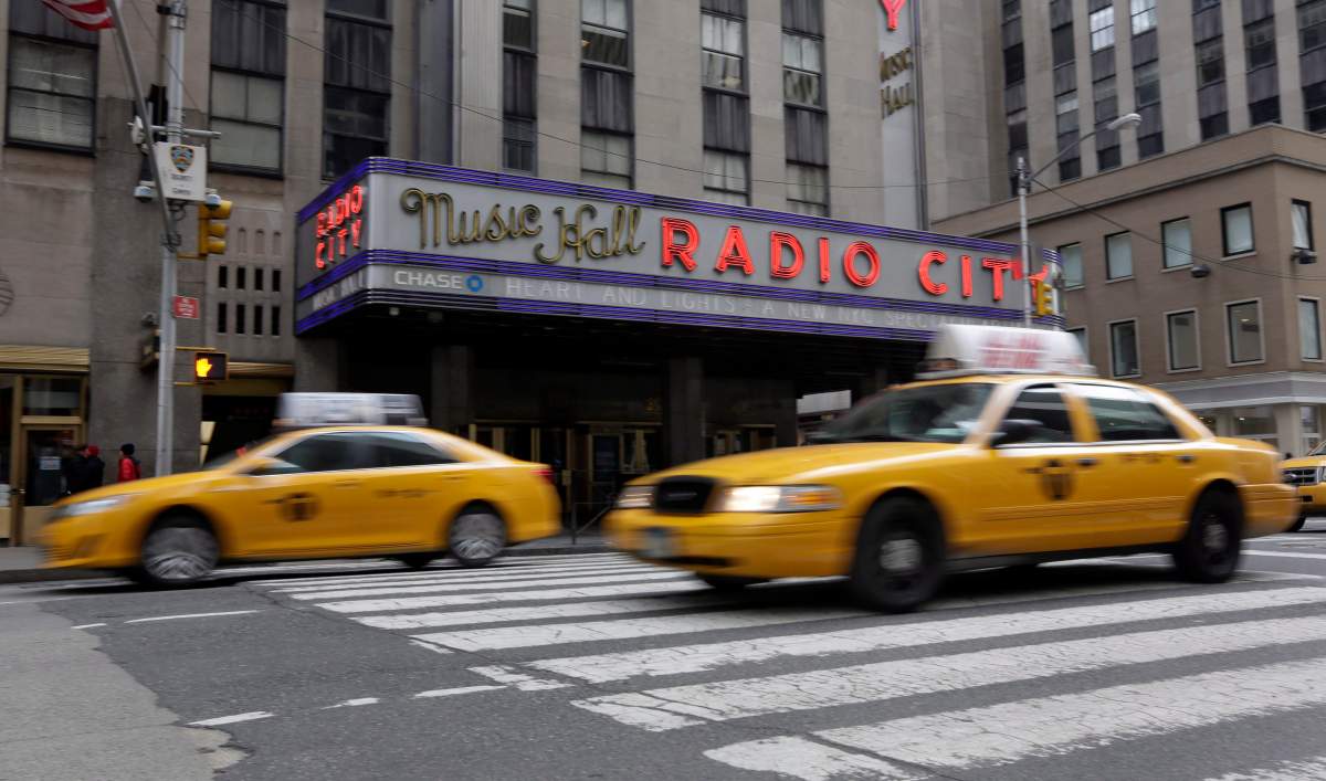 New York City taxis pass New York’s Radio City Music Hall, Thursday, Feb. 27, 2014.