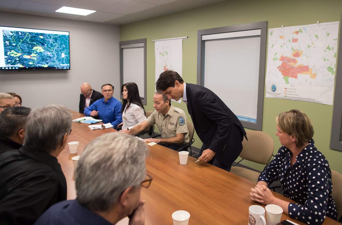 Prime Minister Justin Trudeau, centre right, takes a seat beside B.C. Fire Protection Officer Tom Reinboldt, back centre, for a meeting with officials during a visit to the Prince George Fire Centre, in Prince George, B.C., on Thursday August 23, 2018. THE CANADIAN PRESS/Darryl Dyck