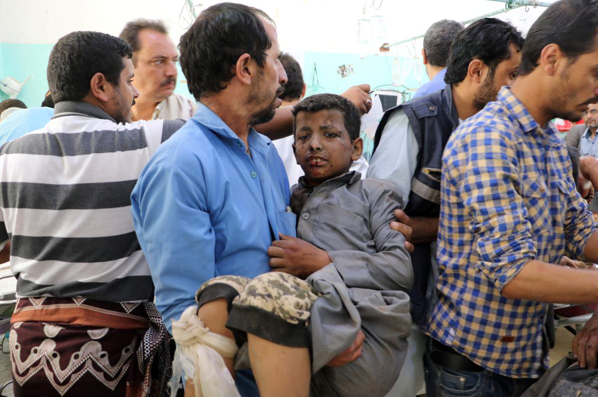 A Yemeni man holds a boy who was injured by an airstrike in Saada, Yemen August 9, 2018.