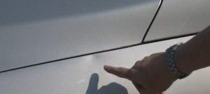 Deirdre Rowland points to the dent on her car after a stray baseball hit it.