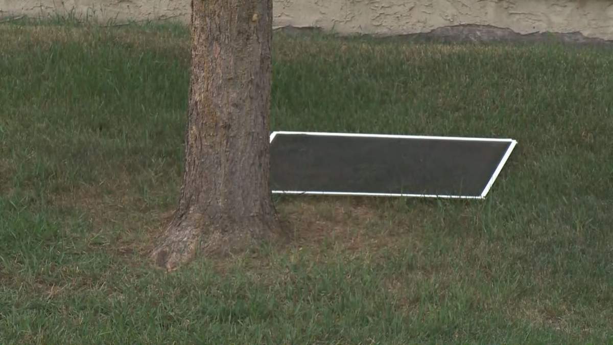A window screen is seen on the grass in front of an Edmonton apartment building after a child fell from the window on Aug. 29, 2018.