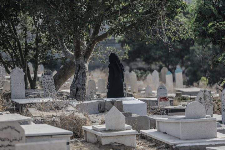 Palestinians visit the grave of their relatives at the cemetery on the first day of Eid al Adha in Gaza City, 21 August 2018.