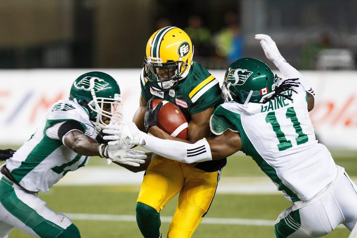 Edmonton Eskimos' Kenny Stafford (8) is tackled by Saskatchewan Roughriders' Marcus Thigpen (8) and Ed Gainey (11) during second half CFL action in Edmonton on Thursday, August 2, 2018.