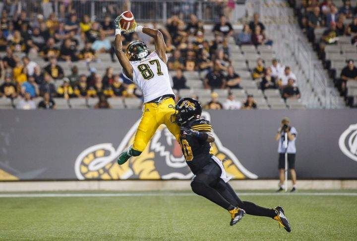 Edmonton Eskimos’ Derel Walker catches a touchdown pass against Hamilton Tiger-Cats’ Mariel Cooper, right, during the first half of CFL football action in Hamilton, Ontario on Thursday August 23, 2018.