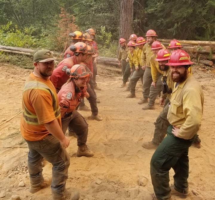 Canadian firefighters, left, and U.S. firefighters meet at the border as they battle the Horns Mountain / Santa Rosa wildfire that’s burning in Washington state and B.C.