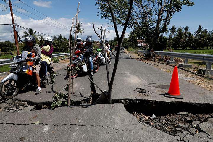 A family rides on a motorcycle through a crack on the street at Kayangan district after earthquake hit on Sunday in North Lombok, Indonesia, August 7, 2018.