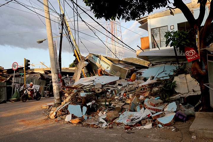 A motorist rides past a house heavily damaged by an earthquake in North Lombok, Indonesia, Tuesday, Aug. 7, 2018.