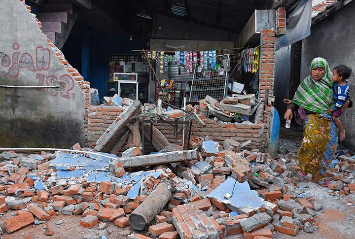 A woman walks past debris from a collapsed wall following a strong earthquake in Lendang Bajur Hamlet, Lombok island, Indonesia August 6, 2018.