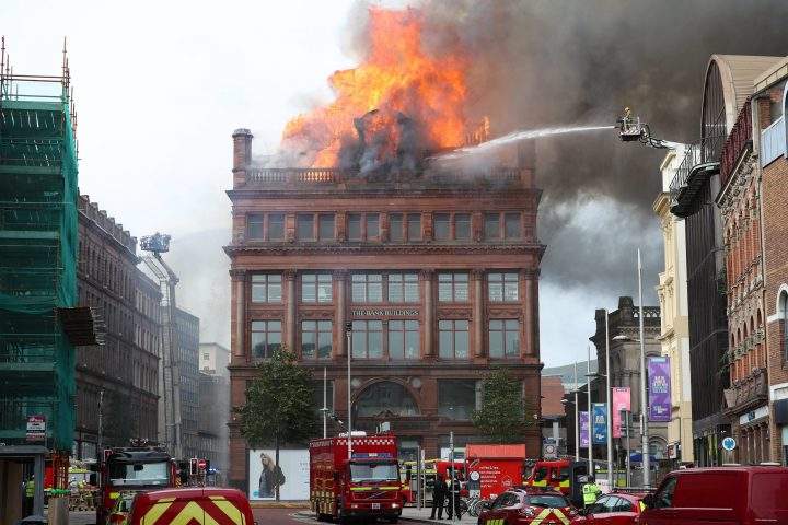 A firefighter trains a hose on a major blaze which has broken out at the Primark store in Belfast city centre, in Northern Ireland, Tuesday Aug. 28, 2018.