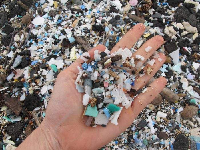 Sarah-Jeanne Royer holds a handful of degraded plastic bits on a beach in Hawaii.