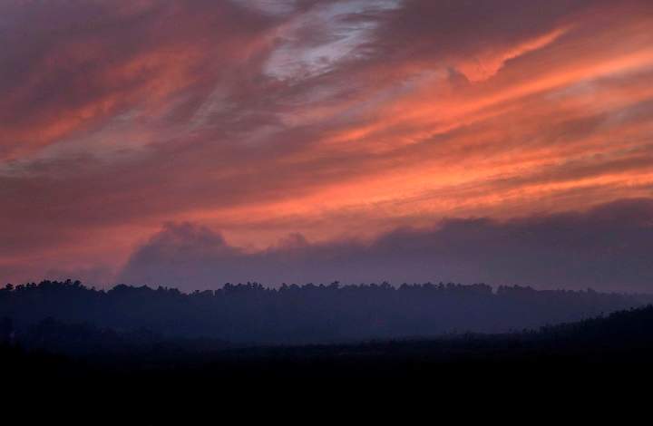 Smoke hangs above the treeline near dusk blocking out the setting sun at forest fires near Killarney, Ont.,  Tuesday, July 31, 2018. There is concern that a change in the weather today could stoke the dozens of wildfires raging across northeastern Ontario.