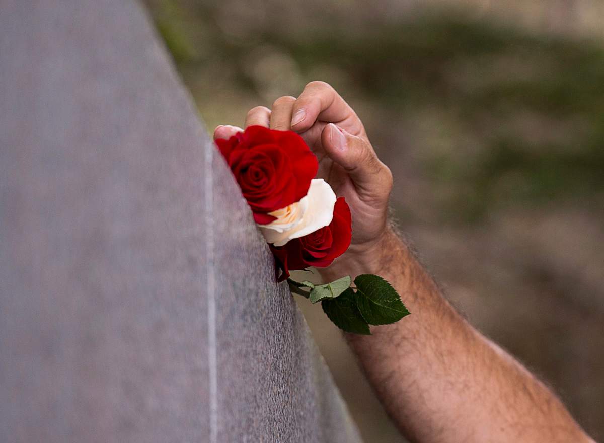 Stephen Thompson, from Atlanta, Ga., places roses on the monument as he remembers his father Ernest Thompson who perished in the crash of Swissair Flight 111 at a memorial service at Bayswater Beach, N.S. on Sunday, Sept. 2, 2018.