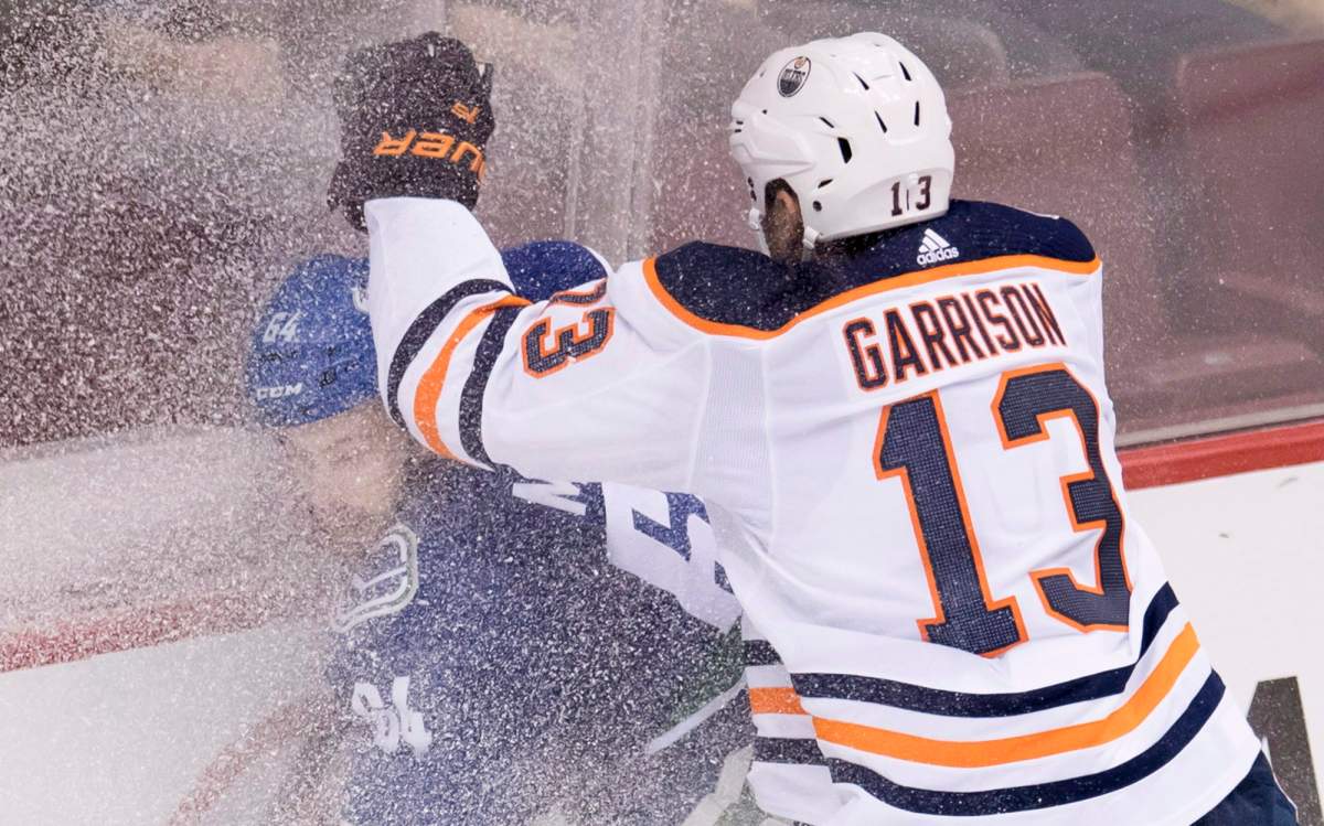 Edmonton Oilers' Jason Garrison covers Vancouver Canucks center Tyler Motte (64) in snow during first period NHL pre-season action at Rogers Arena in Vancouver, Tuesday, Sept, 18, 2018. THE CANADIAN PRESS/Jonathan Hayward.
