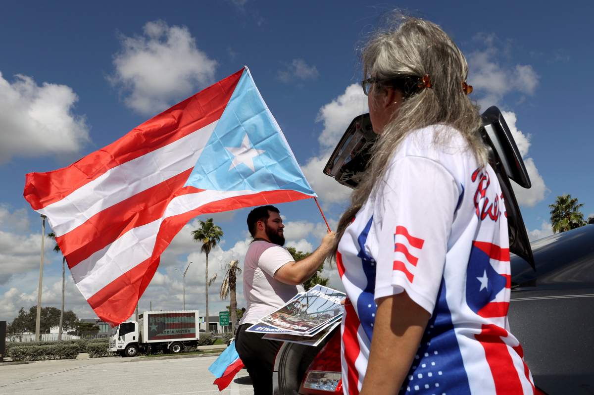 Aaron and Diana Umpirerre gather in the parking lot to meet others to head to West Palm Beach for a protest, Saturday, Sept. 22, 2018 in Hollywood, Fla. 