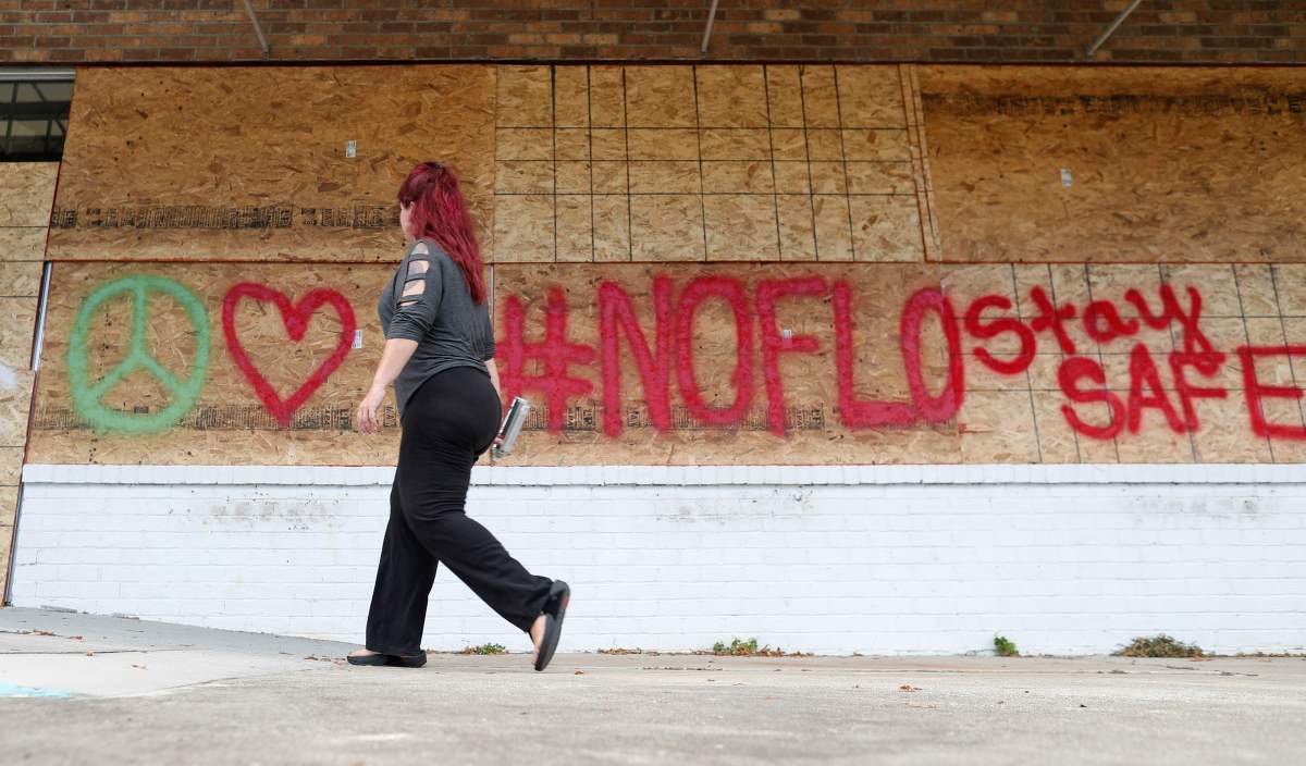 Heather Samson, owner of Beach Beads and Glass Studio, uses spray paint to leave messages on hurricane shutters at her business ahead of the arrival of Hurricane Florence in Surfside Beach, South Carolina, U.S., September 11, 2018.