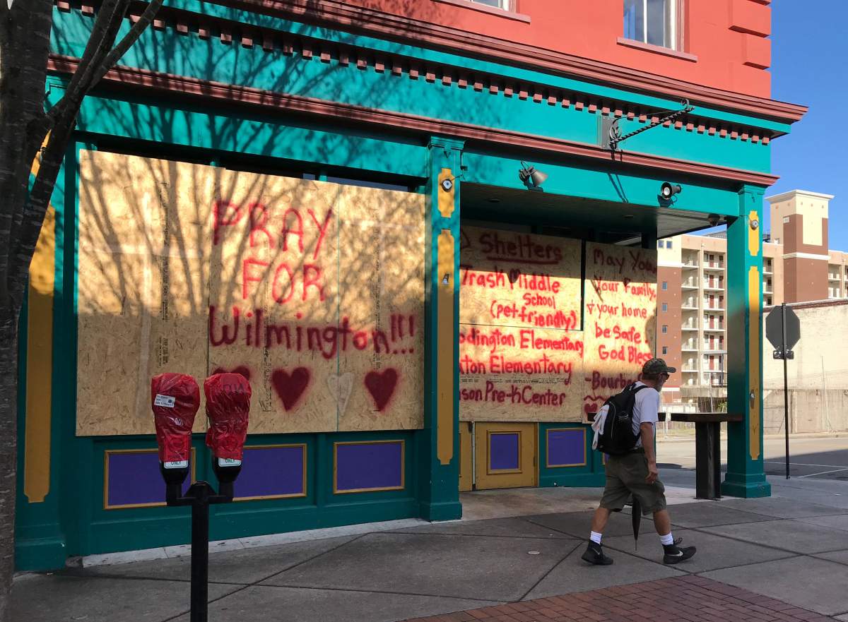 A man passes graffiti reading “Pray for Wilmington” on a business boarded up for the arrival of Hurricane Florence in Wilmington, North Carolina, U.S. September 12, 2018.