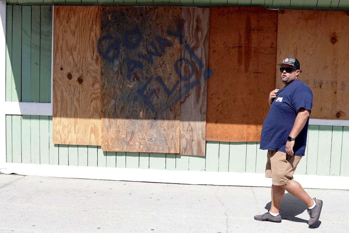 A man walks past a boarded-up store before Hurricane Florence comes ashore in Wrightsville Beach, North Carolina, U.S., September 12, 2018. REUTERS/Carlo Allegri